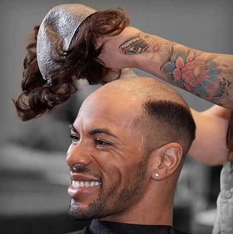 A man with hairloss applying a hair piece